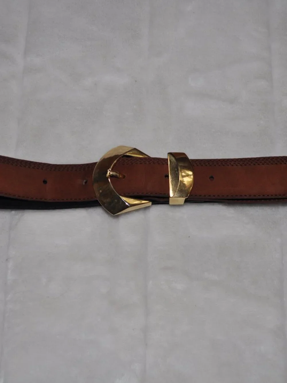 Women's belt features distinctive gold-tone metal hardware, including a unique